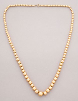 a gold beaded necklace on a white background