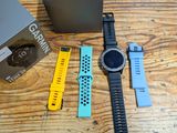 a smart watch sitting on a wooden table next to a box of garmin