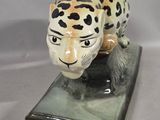 a figurine of a leopard on a green base