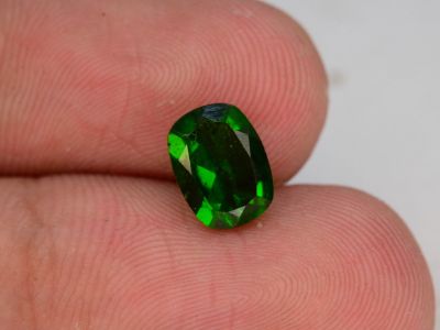 someone is holding a green tourmaline gemstone in their hand