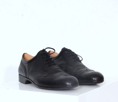 une paire de chaussures noires posée sur une surface blanche