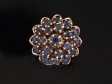 un gros plan d'une bague en or sertie de pierres bleues sur un fond noir