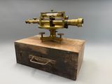 un vieux microscope en laiton posé sur une caisse en bois