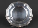 a silver plate on a stand on a black background