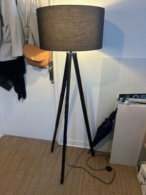 a lamp that is on a tripod next to a coat rack