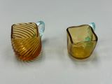 une paire de vases en verre jaune et bleu posés sur une surface blanche