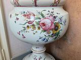 a white vase with a floral design on it sitting on a wooden stand