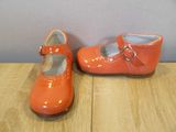 pair of orange toddler shoes with buckles on a wooden surface