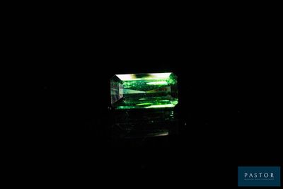 a close up of a green emerald stone on a black surface