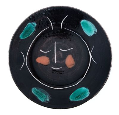 une assiette noire ornée de motifs verts et orange