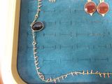 two pairs of earrings and a necklace sitting on a tray