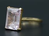 un gros plan d'une bague ornée d'une pierre rose sur un fond noir