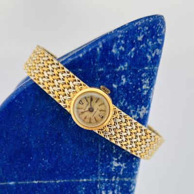 une image représentant une montre-bracelet pour femme posée sur un vase bleu