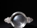 an antique silver plate on a stand against a black background