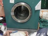 une machine à laver posée par terre à côté d'une pile de vêtements