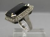 a close up of a ring with a black stone surrounded by white diamonds