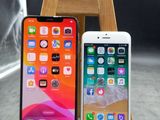 deux iPhones posés sur un support en bois à côté d'un verre d'eau