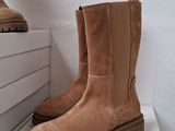 two pairs of brown boots sitting on top of a white box