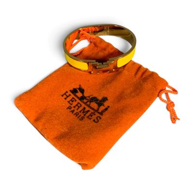 un sac orange orné d'un anneau, posé sur une surface blanche