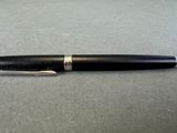 a pen that is laying on a table next to a cell phone