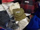 une valise remplie de vêtements, tous entassés les uns sur les autres