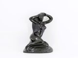 statue of a woman sitting on a rock with her hands on her head