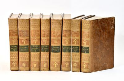 six old books are lined up in a row on a white surface