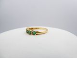 a close up of a gold ring with three emerald stones