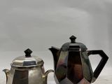 two silver teapots and a silver teapot sitting on a table