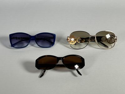 three pairs of sunglasses are sitting on a white surface