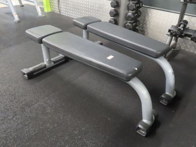 a bench and weights in a gym with a wall in the background
