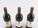 three bottles of wine are lined up on a white surface