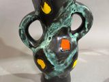 un vase noir et vert parsemé de taches orange