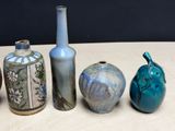 five different vases sitting on a table with a black wall in the background