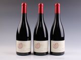 trois bouteilles de vin rouge posées sur une table blanche