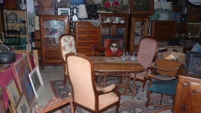 une pièce avec une table, des chaises et des photos posées par terre