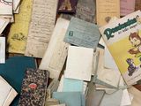 a pile of old books on the floor next to a pile of papers