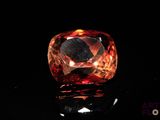 a close up of an orange diamond on a black surface