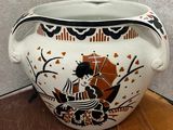 a white vase with a black and orange design on it