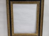 a gold and black picture frame sitting on a white surface