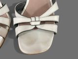 a pair of white sandals with a bow on them