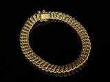 a gold chain bracelet with a clasp on a black background