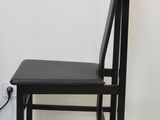 a black chair sitting next to a white wall