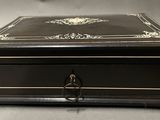 an antique black and gold jewelry box sitting on top of a table