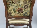 an old chair with a floral upholstered back and a wooden frame