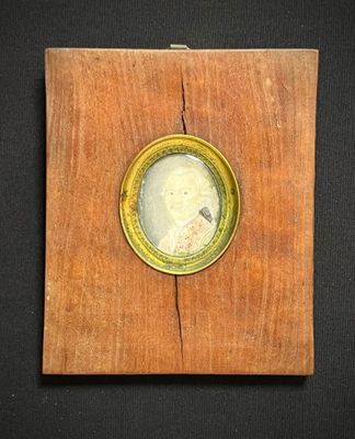 un vieux cadre en bois sur lequel est posée une petite horloge, posé sur une surface noire