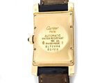 a gold watch with a brown leather strap on a white surface