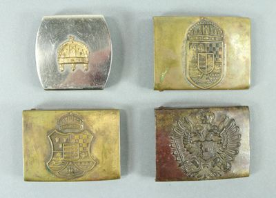 four different types of silver and gold belt buckles on a white surface