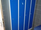 blue lockers in a bathroom with a blue chair and a trash can