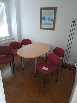 several chairs around a table in a room with a picture on the wall